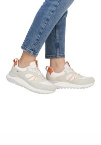 Zapatillas blancas y grises que presentan paneles de gamuza y malla. Acentuadas con color naranja en el talón y los cordones. Suela de goma gruesa y texturizada.