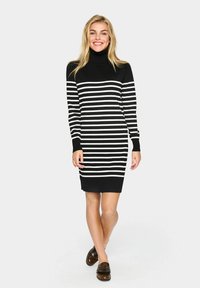 Black turtleneck dress with white horizontal stripes, fitted design, and ribbed cuffs. Worn with brown loafers.