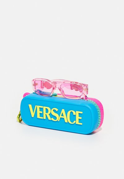 Óculos de sol rosa claros em cima de uma caixa azul com o logótipo amarelo "Versace". A caixa possui um fecho rosa e detalhes verdes, com uma textura suave em plástico.
