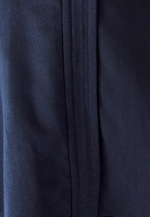 Suur lähivõte tumedast sinisest kangast, millel on nähtavad õmblused ja vertikaalselt kulgev keskmine õmblus.