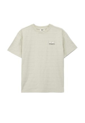 Vaaleanbeige lyhythihainen t-paita pyöreällä kaula-aukolla, jossa hienovaraiset vaakaraitakuviot ja pieni suorakaiteen muotoinen merkki vasemman rinnan kohdalla.