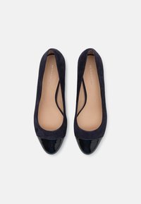 Navy suede ballet flats featuring a glossy black patent leather toe cap and soft interior lining, with a wide opening for easy foot entry.