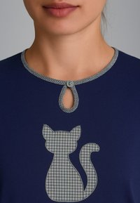 Top in cotone blu navy con scollatura a occhio di bue, rifinito con un bordo a quadretti grigi e un'applicazione di un gatto con un motivo simile.