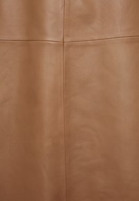 Tan læderstof med en glat tekstur, der har subtile sømme og et minimalistisk design, der viser en varm, neutral tone.