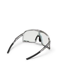 Priehľadné slnečné okuliare s pevným rámom, čiernymi gumovými ramenami, priehľadnými šošovkami a mierne zakriveným dizajnom pre pevné uchytenie.