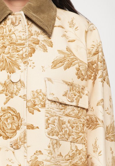 Beige Jacke mit Blumenmuster und strukturiertem braunem Cordkragen, ausgestattet mit einem Knopfverschluss und einer aufgesetzten Tasche.