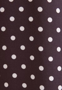 Tissu foncé avec de petits pois blancs espacés régulièrement formant un motif régulier.