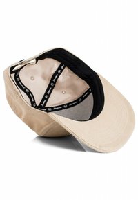 Beige cap with a curved brim, black interior lining, and a logo tape inside. Features a smooth fabric texture and ventilation openings.