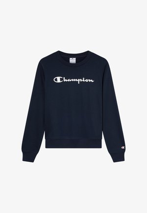 Sudadera azul marino de algodón, con un logo blanco de "Champion" en el pecho y un detalle de la marca en el puño. Cuello redondo, mangas largas.