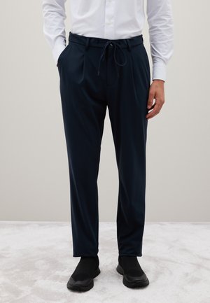 Pantalons bleu marine à coupe décontractée avec une taille élastique, fermeture à cordon de serrage et poches latérales. Le matériau semble lisse et léger.