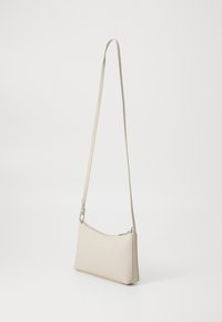 Borsa crossbody rettangolare beige con una texture liscia, spallaccio sottile e chiusura con zip. Design minimalista con accenti sottili.