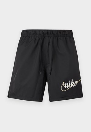 Pantaloncini sportivi neri con vita elasticizzata e cordoncino, caratterizzati da un grande logo Nike beige sulla parte inferiore della gamba destra.