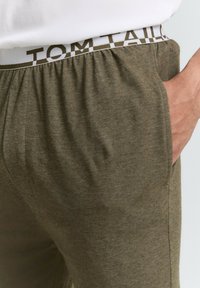 Olijfgroene joggingsbroek van een katoenmix met elastische tailleband met witte "TOM TAILOR" logo. Zijzakken, relaxed fit, textuurstof.