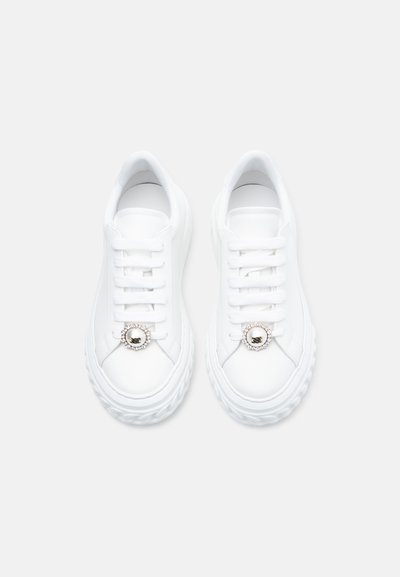 Λευκά αθλητικά παπούτσια με λείο δερμάτινο φινίρισμα, στρογγυλεμένη μύτη, χοντρή σόλα και διακοσμητικό κυκλικό μεταλλικό στοιχείο στα κορδόνια.
