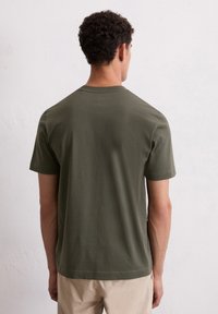 Olijfgroene katoenen t-shirt met korte mouwen, een ronde hals en een gladde textuur. De achterkant toont de schoudernaden en een eenvoudig design.