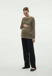 Olive green long-sleeve top with a gathered waist, paired with black loose-fitting pants and black shoes. Simple design and soft texture.