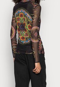 Black mesh long-sleeve top featuring vibrant floral and paisley patterns in green, red, and blue. Form-fitting design with high neck.
