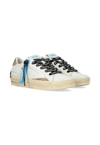 Sneakers in pelle bianca con un accento dorato brillante, lacci neri con marchio e etichette blu. Superficie texturizzata con una suola beige consumata.