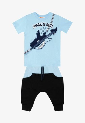 Lichtblauwe katoenen t-shirt met een haai die gitaar speelt, gecombineerd met zwarte joggerbroeken met een elastische tailleband en zakken.