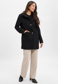 Black wool blend coat with a collar, three buttons, and pockets, featuring a slightly structured design and soft texture.