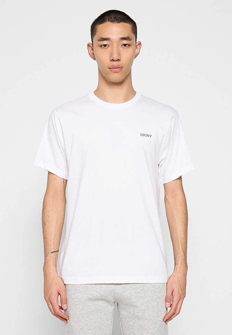 Biała koszulka z krótkim rękawem wykonana z bawełny, z okrągłym dekoltem i małym szarym logo DKNY na lewej stronie klatki piersiowej.