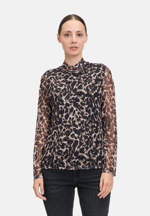 Maglia a maniche lunghe in tessuto trasparente con stampa leopardo nera e beige, colletto alto e vestibilità aderente, abbinata a jeans scuri.