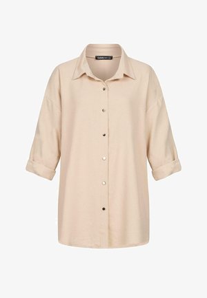 Chemise boutonnée couleur crème en tissu doux ; elle possède un col classique, des manches trois-quarts retroussées et des accents de boutons noirs.