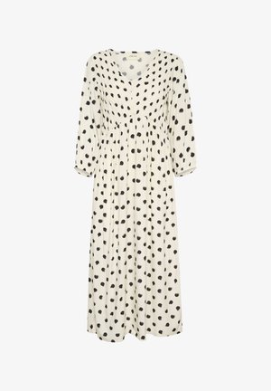 Valge kleit mustade täppidega, V-kaelus, pikad varrukad elastsete mansettidega, kokku volditud talje ja voogav seelik.