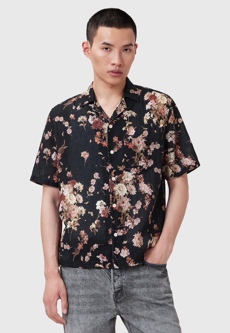 Cămașă cu nasturi din țesătură neagră, decorată cu un model floral în nuanțe de roz, alb și galben. Mâneci scurte și un detaliu de buzunar pe piept.