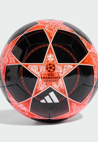 Pallone da calcio nero e rosso con motivo geometrico a stella. Presenta il logo della UEFA Champions League e il marchio Adidas su una superficie lucida.