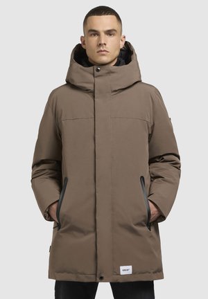 Parka mat brune avec un col haut, une grande capuche, des poches avant et des accents noirs. Texture lisse avec des détails de couture visibles.