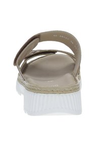 Beige sandal with two fabric straps, woven detailing, and a white textured rubber sole. The design is open at the back for easy wear.