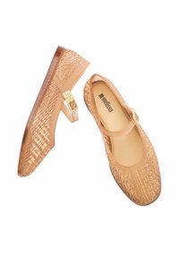 Bailarinas beige translúcidas tipo Mary Jane con textura trenzada, punta redonda y correa ajustable con herrajes en tono dorado. Forro interior suave.