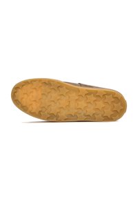 Suela de zapato de goma con parte superior de color beige marrón. La suela presenta un patrón de banda de rodadura en forma de estrella y un borde liso. Diseño duradero y texturizado.