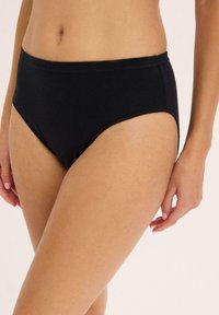 Culotte en coton noir avec taille haute et texture lisse. Elle présente des coutures minimales et une coupe de culotte classique sans motifs visibles.