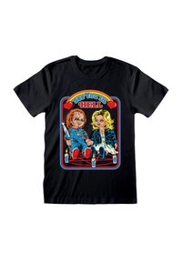 Sort T-shirt med tegneserie af en uhyggelig dukke, der holder en kniv, og en blond kvindedukke, der sidder på et pentagram omgivet af tændte stearinlys.