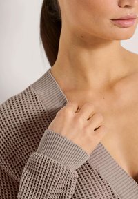 Hellbrauner, gestrickter Cardigan mit einer strukturierten, offenen Webart und gerippten Bündchen. V-Ausschnitt-Design, leicht am Schlüsselbein gehalten.