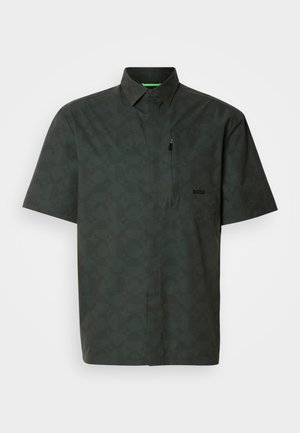 Chemise à manches courtes de couleur vert foncé avec un motif géométrique. Elle présente un col, une poche avant, un accent zippé et un logo discret sur la poitrine.