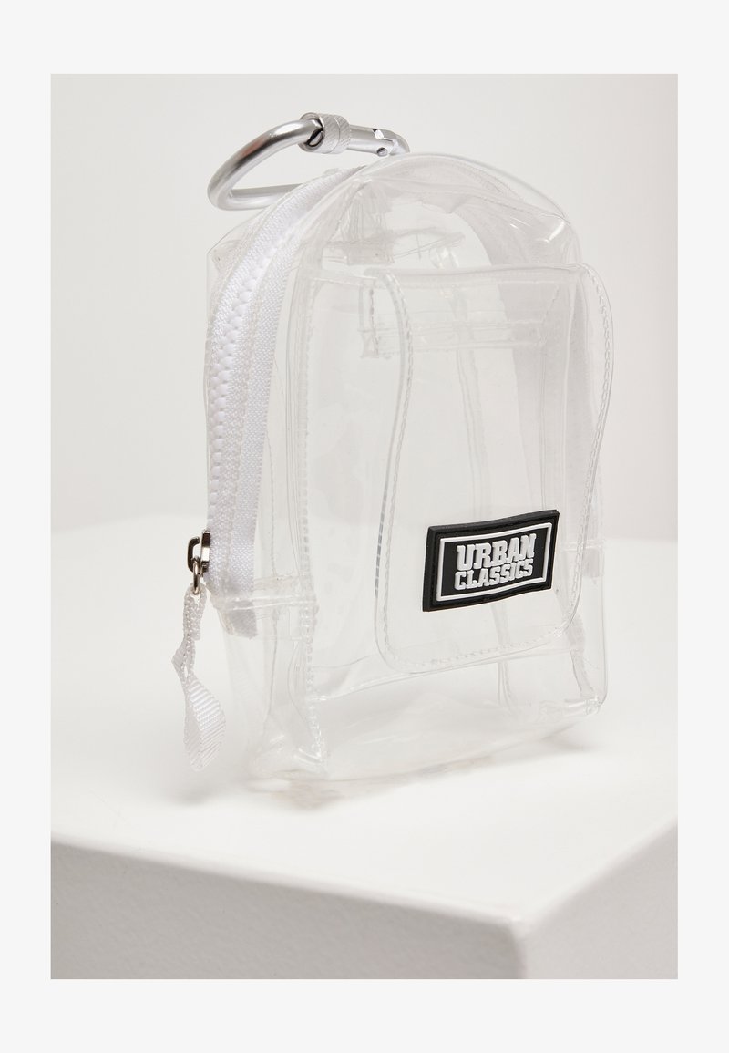 Mini sac à dos en PVC transparent avec fermeture éclair et sangle blanches. Comprend un écusson de logo noir et un mousqueton en argent. Forme rectangulaire compacte.