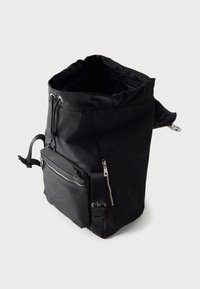 Το μαύρο σακίδιο διαθέτει ένα απαλό, αδιάβροχο υλικό, άνοιγμα με ρολό, ρυθμιζόμενους ιμάντες και μπροστινή τσέπη με φερμουάρ.