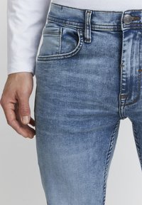 Ljusblå denimjeans med en klassisk design, som har framfickor, en metalldetalj för stängning och synliga sömnadsdetaljer.