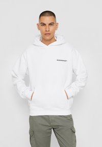 Hvid hættetrøje med en frontlomme og snørehætte, med en sort logo "MJGONZALES™" trykt på venstre bryst.