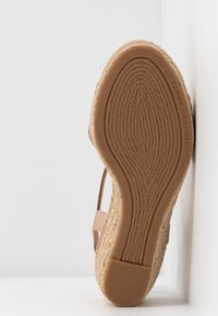 Semelle de sandale avec motif tissé texturé, talon en caoutchouc, et nom de la marque "Tommy Hilfiger" embossé le long du bord latéral.