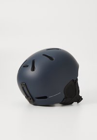 Tmavomodrá prilba s ventilačnými otvormi a nastaviteľnými popruhmi. Má hladký matný povrch a logo na boku.