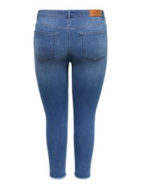 Jean skinny bleu en denim vu de dos avec deux poches arrière et un patch de marque en cuir marron sur la ceinture.