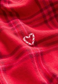 Czerwono-skalnowany materiał z małym, białym haftowanym serduszkiem. Miękka faktura z subtelnymi zmianami w wzorze.