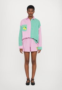 Stribet skjorte i pink og grøn med en citron grafisk lomme, parret med matchende stribede shorts. Glat stof og afslappet pasform.