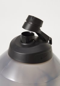 Nike gennemsigtig plastvandflaske med et sort skruelåg og en tud. Har et sort greb og et logo på siden. Glat tekstur.