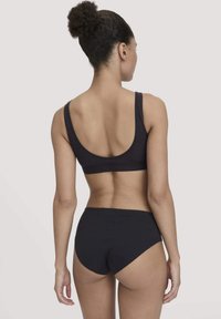 Zwarte katoen sportbeha met brede bandjes en een scoop rug, gecombineerd met bijpassende high-waisted slips, die een gladde textuur en een slim fit ontwerp tonen.