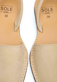 Beige slip-on sandals with a smooth leather upper, featuring stitched detailing and a soft insole, size 38, minimalist design.